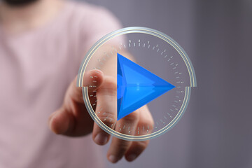 Person uses finger to select a blue play button on a futuristic interface.  Technology, media,...