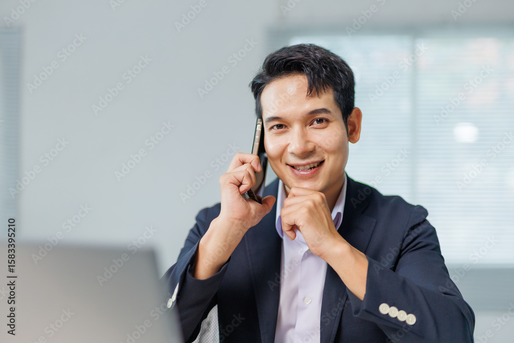 Poster portrait of happy manager speaking on mobile phone and looking at camera while working on laptop in 