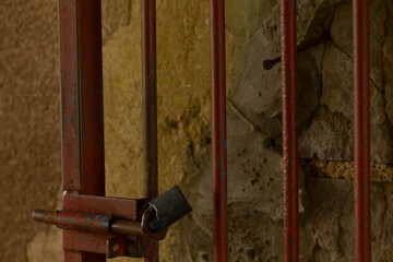 This image presents a closeup view of a strong metal gate that features a sturdy padlock fastened...