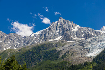 Obraz premium Chamonix valley landscape of a prominent rocky towering mountain peak Aiguille du Midi in French Alps. Chamonix-Montblanc area, Tour du Montblanc beautiful landscape Aiguille du Midi summit, France
