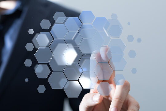 Abstract image of a businessman interacting with a digital hexagon network.  Represents technology, connection, and inno