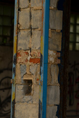 There exists a sturdy brick wall, and in front of it stands a vibrant blue pole that draws attention to the scene