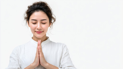 Joyful Asian woman in white shirt practicing meditation eyes closed and hands in namaste position on bright white clean background