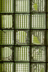 This is a detailed closeup image of a broken glass block window, which showcases the unique textures and reflections as well as the fractured pieces