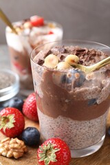 Taking delicious chocolate pudding with chia seeds, blueberries and hazelnuts from glass on table, closeup
