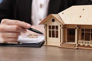 Real estate agent working at desk with house model in office, closeup