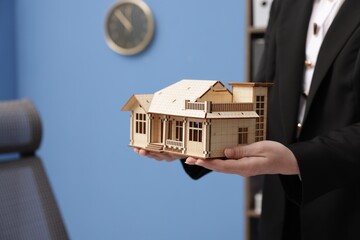 Real estate agent holding house model in office, closeup
