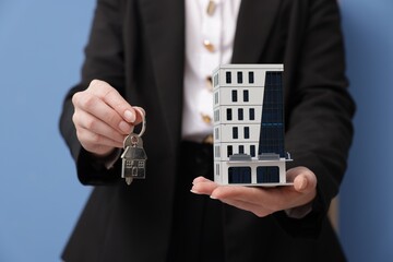 Real estate agent holding house model and key in office, closeup
