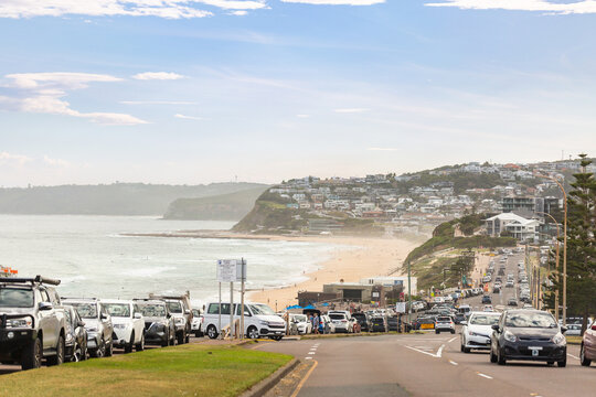 traffic on coastal road passing free public carpark for Australian beach on hazy afternoon