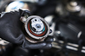 Auto part. Professional mechanic with idler-wheel near open hood of car indoors, closeup. Space for...