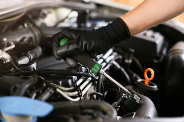 Auto parts. Professional mechanic with screwdriver fixing car indoors, closeup