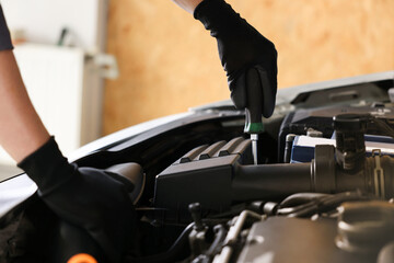Auto parts. Professional mechanic with screwdriver fixing car indoors, closeup