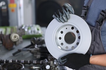 Auto parts. Professional mechanic with brake disc indoors, closeup