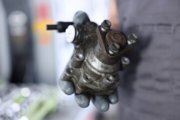 Auto part. Professional mechanic with power steering pump indoors, closeup. Space for text
