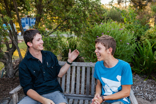 Happy smiling brothers playing hand slapping game outside in backyard