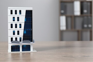 Real estate. Apartment building figure on wooden table indoors, space for text