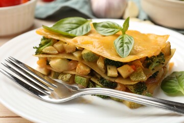 Piece of tasty vegetarian lasagna served on white wooden table, closeup