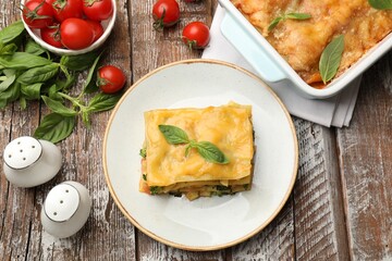 Piece of tasty vegetarian lasagna and ingredients on wooden table, flat lay