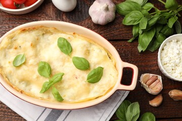 Tasty vegetarian lasagna and ingredients on wooden table, flat lay