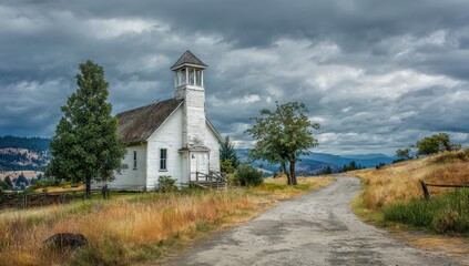 Fototapeta premium Old white church sits on a hilltop with a dirt road and stormy skies overhead
