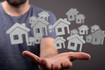 Image of a man's hand holding multiple house icons, symbolizing real estate, property, and home...