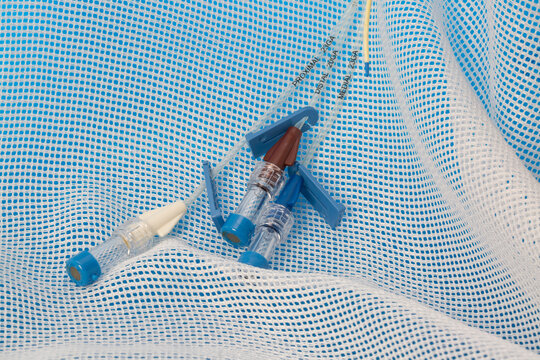 Triple lumen short-term central venous catheter with three infusion channels reflected on blue background covered by medical gaze