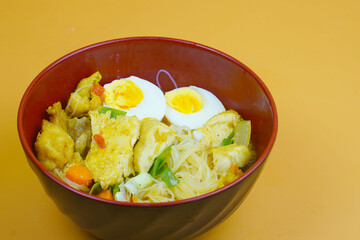 A vibrant bowl of Bihun Kari or Indonesian curry vermicelli noodles, chicken, eggs, and vegetables...