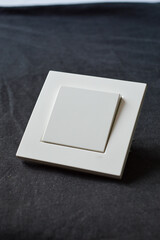 white plastic light switch held in hand on black background, minimalistic electrical component...