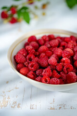 Plate of freshly picked raspberries on white wooden background. Concept of harvest, healthy organic...