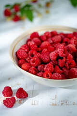 Plate of freshly picked raspberries on white wooden background. Concept of harvest, healthy organic...