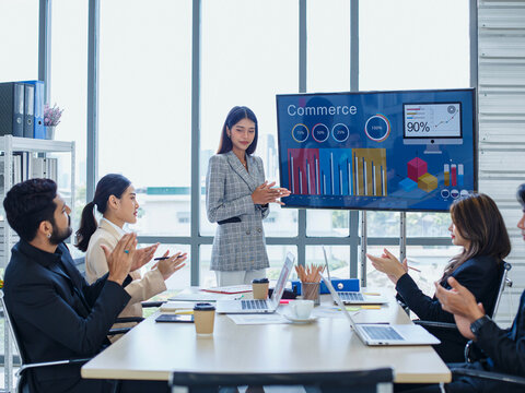 Group of diverse business professionals in modern office attending strategy meeting while Asian businesswoman presents marketing data on large screen. Strategic planning concept, - Powered by Adobe