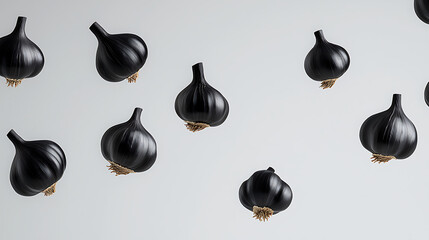 A modern layout of shiny black garlic bulbs on a light background provides an interesting culinary concept that is visually appealing and memorable.