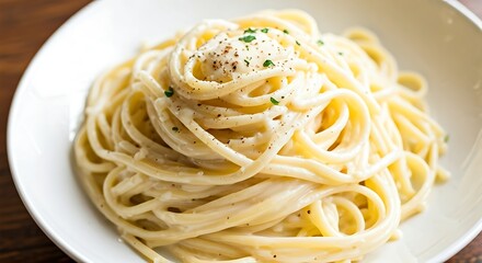 A tempting plate of spaghetti carbonara is delicately plated and topped with fresh herbs and spice.