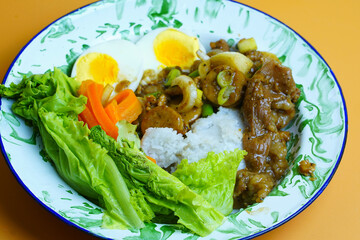 A delicious meal with white rice, savory stir fried beef and hard-boiled eggs, fresh lettuce, and...