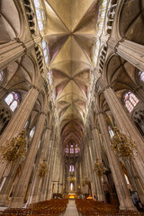 Naklejka premium Bourges Cathedral nave showing gothic architecture, stained glass windows and chandeliers in France