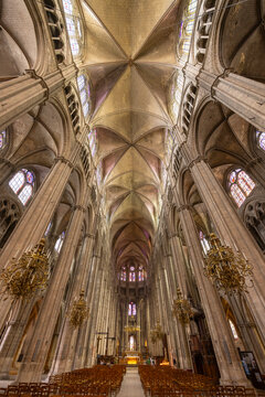 Bourges Cathedral nave showing gothic architecture, stained glass windows and chandeliers in France