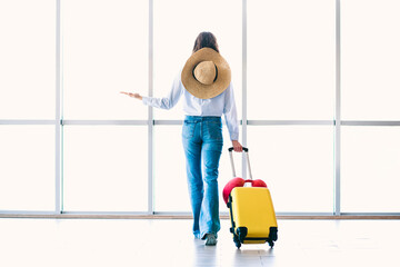 Charming woman with luggage waiting at the airport in casual attire, representing travel,...