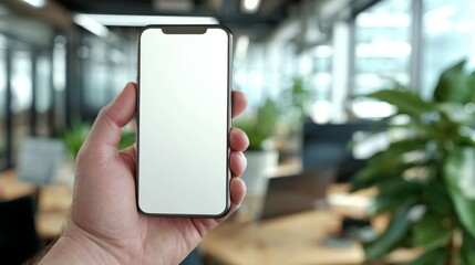 Person Holding Blank Smartphone in Modern Office Environment with Green Plants and Contemporary Workspace Background