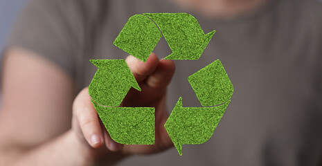 Eco-friendly concept.  Hand interacting with a green recycle symbol made of grass.