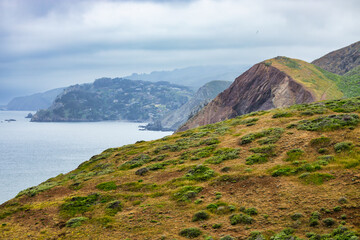 Rolling green hills and rugged cliffs rise above the Pacific Ocean along the Rodeo Beach Coastal...