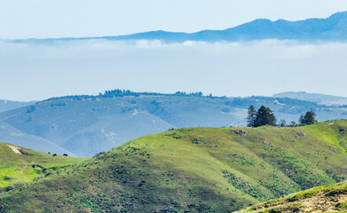 Distant view of layered green hills and Mount Toro near Soberanes Canyon Trailhead in California,...