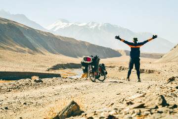 Adventurous caucasian male traveller arms up enjoy views cycle bicycle touring solo on gravel...