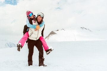 Joyful young loving couple walk piggyback smiling in deep snow share romantic bonding on snowy mountain, love, happiness, freedom, playful relationship, romantic adventure, carefree winter escape