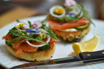 Bread topped with smoked salmon, avocado, cucumber, arugula, onions, and edible flowers. Served...
