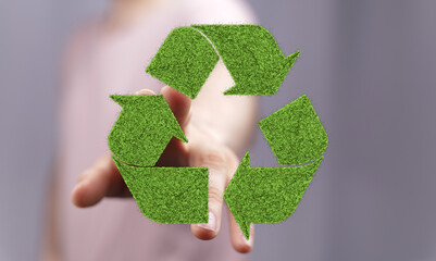 Hand holding a recycling symbol made of grass. Eco-friendly concept. Sustainable lifestyle.