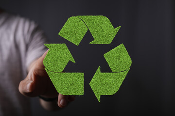 Hand interacting with a green recycling symbol, eco-friendly concept.