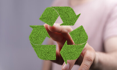 Eco-friendly recycling concept.  Hand interacting with a green grass recycle symbol. Sustainable...