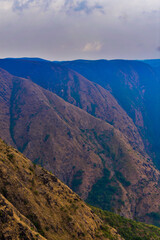 Layered mountain ranges under a dramatic sky, showcasing vast rugged landscapes and natural beauty...