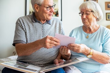 Elderly couple looking at photos. Senior man and woman sharing memories. Happy elderly couple enjoying time together. Senior couple with photo album. Senior man and woman looking at photos in album.