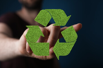 Image of a hand holding a green recycle symbol, promoting eco-friendly practices.